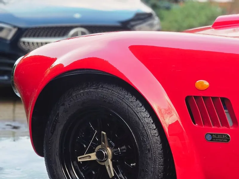 Close-up of black alloy wheel on a red AC Cobra