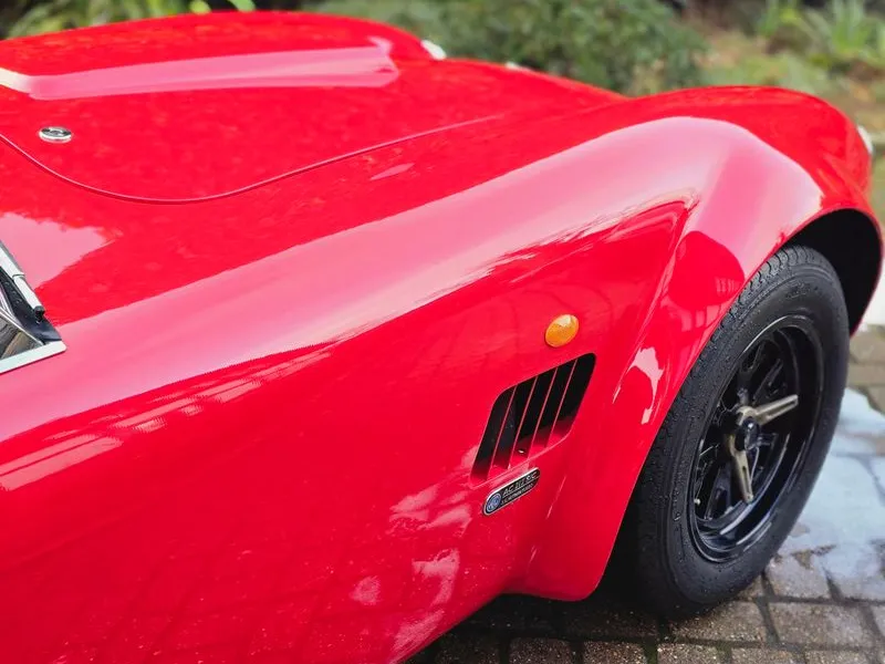 Bright red AC Cobra front quarter view covered in snow foam