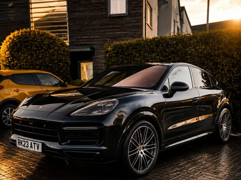 Black Porsche Cayenne Coupe front three-quarter view on wet pavement