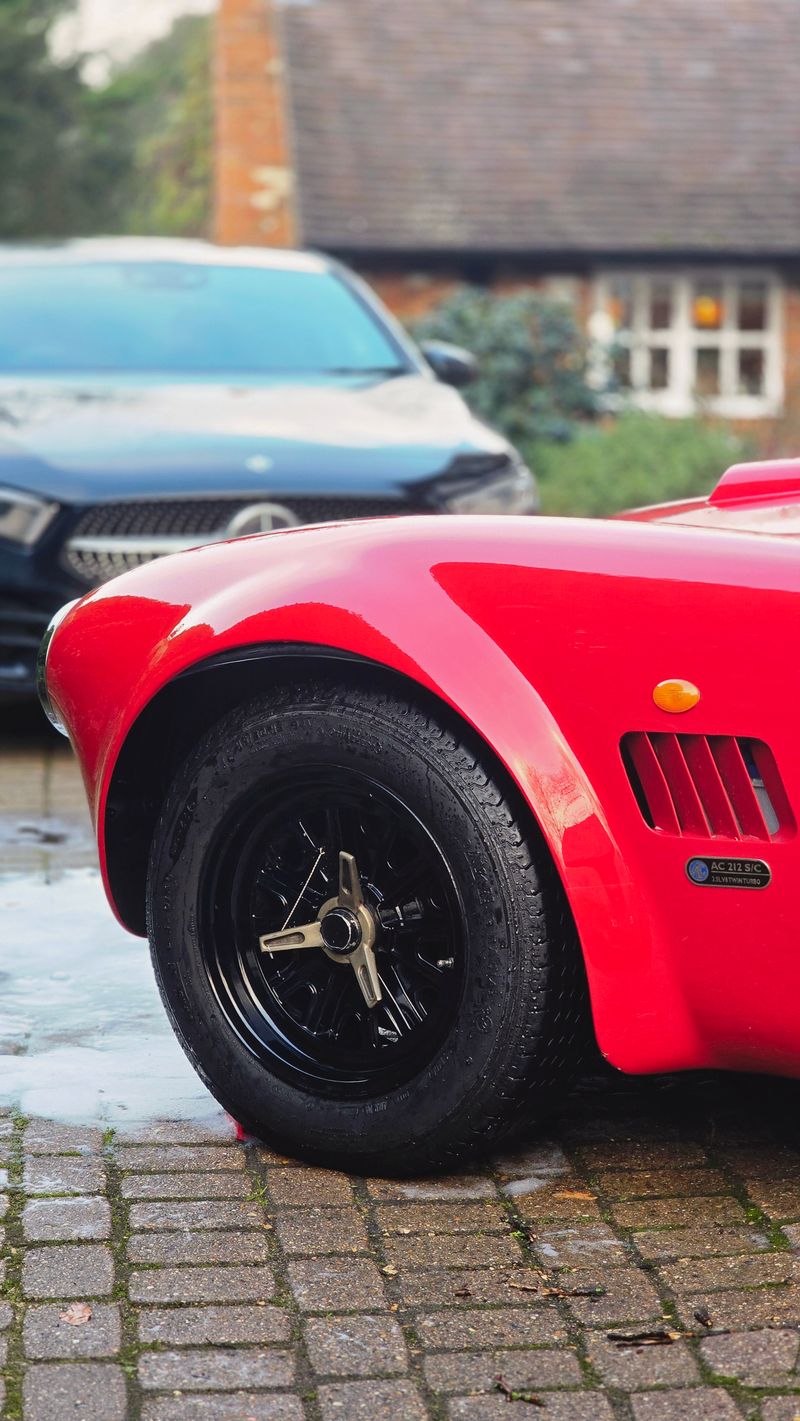 Close-up of black alloy wheel on a red AC Cobra