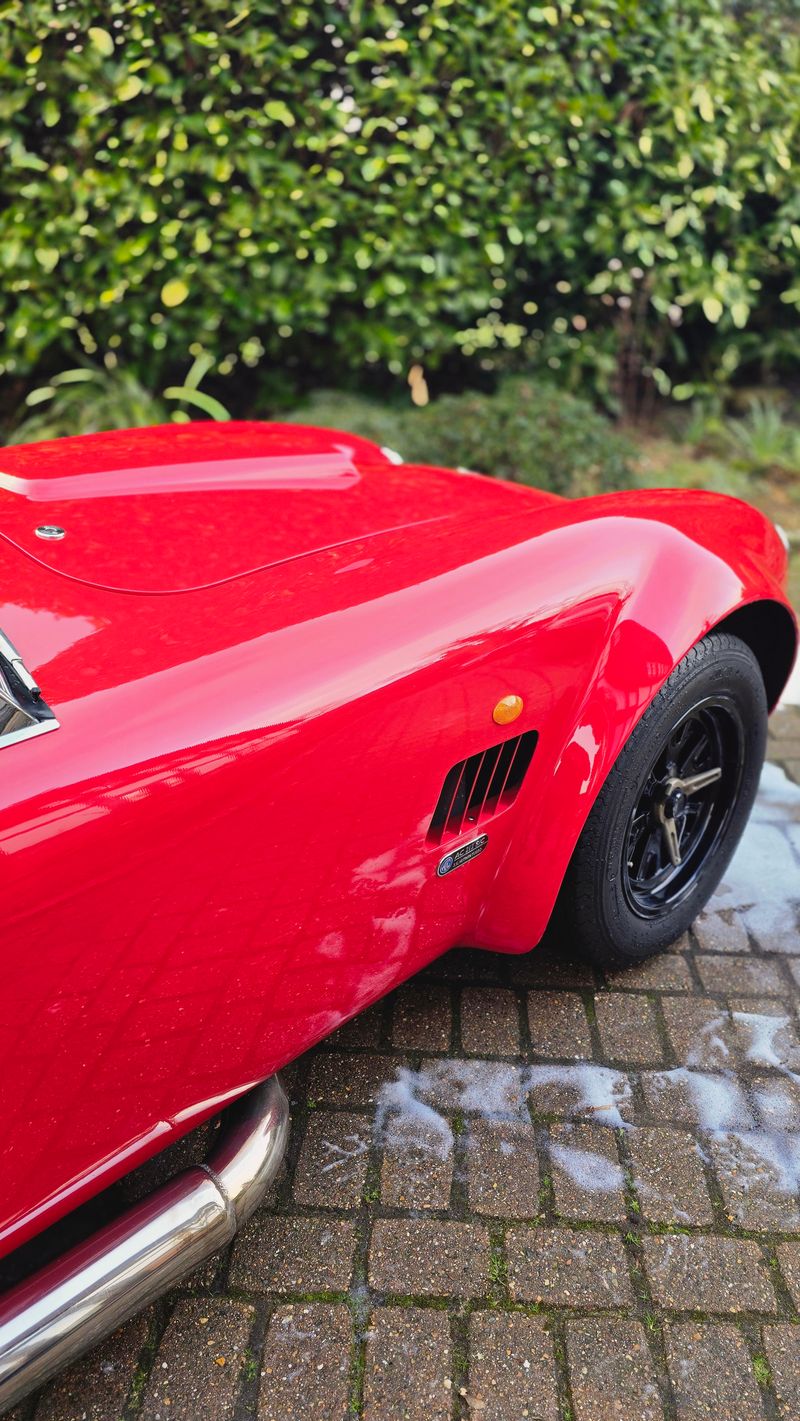 Bright red AC Cobra front quarter view covered in snow foam